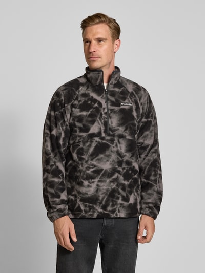 Männermodel trägt Fleecepullover mit Label-Details Modell 'Timber Crest™' von Columbia in Schwarz-Grau, Nahaufnahme Oberkörper. Gerader Schnitt, Stehkragen, Reißverschluss, Rückenlänge 70 cm, Ärmellänge 73 cm.