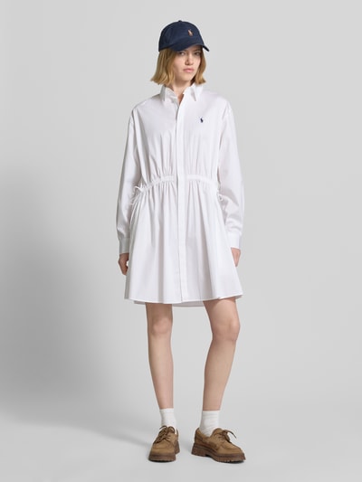 Frauenmodel trägt Tailliertes Hemdblusenkleid aus reiner Baumwolle von Polo Ralph Lauren in Weiß, unifarben, Mini-Länge, Ganzkörperansicht von vorne.