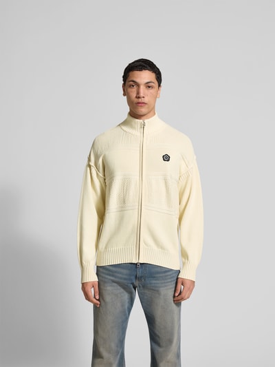 Männermodel trägt Relaxed Fit Strickjacke mit Woll-Anteil von Kenzo in Creme mit Label-Patch, gerippte Abschlüsse, Ganzkörperansicht von vorne. Rückenlänge 69 cm, Schulterbreite 64 cm, Ärmellänge 57 cm, Baumwoll-Woll-Mix.
