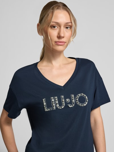 Frauenmodel trägt Regular Fit T-Shirt aus reiner Baumwolle von Liu Jo White in Dunkelblau mit Ziersteinbesatz und Logo-Detail, Nahaufnahme Oberkörper.