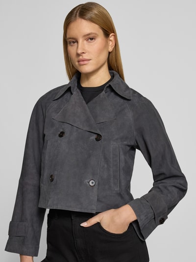 Kobiece modelka nosi Regular Fit Trenchcoat aus echtem Ziegenleder von Marc O'Polo w optyce zamszowej, krój regular fit, długi rękaw, kieszenie boczne, materiał: prawdziwa skóra kozia, detal: podwójny rząd guzików, kolor ciemnoszary, faktura matowa, całkowity widok z przodu.