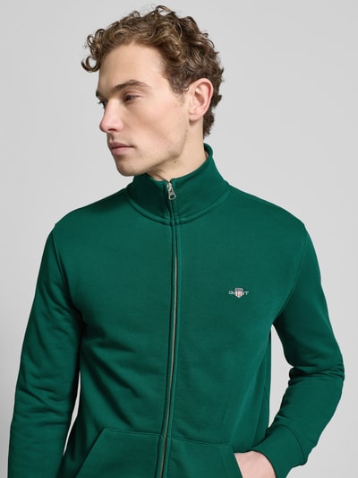 Männermodel trägt grüne Sweatjacke mit Label-Stitching von Gant, Baumwoll-Mix, Regular Fit, Stehkragen, Nahaufnahme Oberkörper.