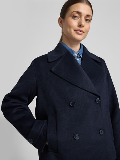 Frauenmodel trägt Kurzmantel mit Reverskragen und Eingrifftaschen von Stefanel, dunkelblau, Material-Mix mit Leinen, Nahaufnahme Oberkörper.