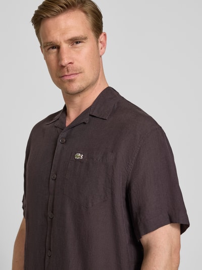 Männermodel trägt Relaxed Fit Leinenhemd mit Resortkragen von Lacoste in Uni-Braun, reines Leinen, Logo-Stitching, Nahaufnahme Oberkörper