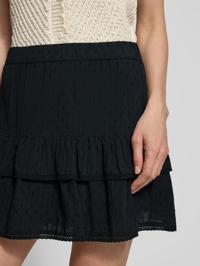 Frauenmodel trägt Volant Mini-Rock aus reiner Baumwolle 'TRINE' von Vero Moda, schwarz, gepunktet, Popeline, Nahaufnahme Oberkörper.
