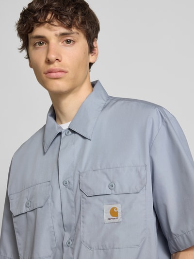 Männermodel trägt Relaxed Fit Freizeithemd mit Kentkragen und Label-Detail von Carhartt Work In Progress, Baumwoll-Anteil, Nahaufnahme Oberkörper.