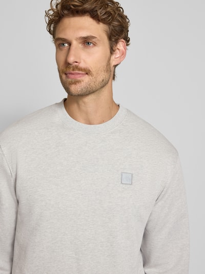 Männermodel trägt Regular Fit Sweatshirt aus reiner Baumwolle mit Label-Patch von Scotch & Soda, helle Farbe, Nahaufnahme Oberkörper. Rückenlänge bei Größe M: 70 cm, Ärmellänge bei Größe M: 66 cm, elastische Abschlüsse.