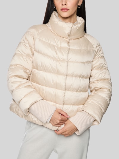 Frauenmodel trägt Steppjacke mit Stehkragen und Label-Detail von Marc Cain in Beige, glatte Struktur, Quersteppung, Nahaufnahme Oberkörper, Regular Fit, Eingrifftaschen, KI-modifiziertes Bild.
