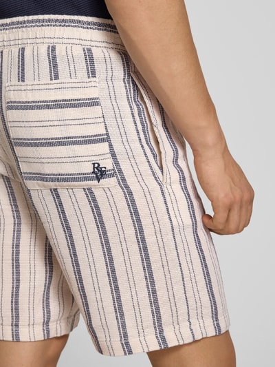 Männermodel trägt Shorts mit elastischem Bund und Logo-Detail von REVIEW, gestreiftes Baumwoll-Mix-Design, Nahaufnahme Oberschenkel.