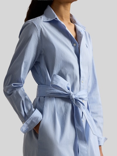 Frauenmodel trägt tailliertes Hemdblusenkleid aus reiner Baumwolle von Polo Ralph Lauren, hellblau, langarm, Logo-Stitching, Nahaufnahme Oberkörper.