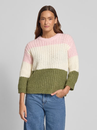 Frauenmodel trägt Strickpullover mit Rundhalsausschnitt von More & More in Rosa, Creme und Oliv, Grobstrick, Relaxed-Fit, Material-Mix, Nahaufnahme Oberkörper.