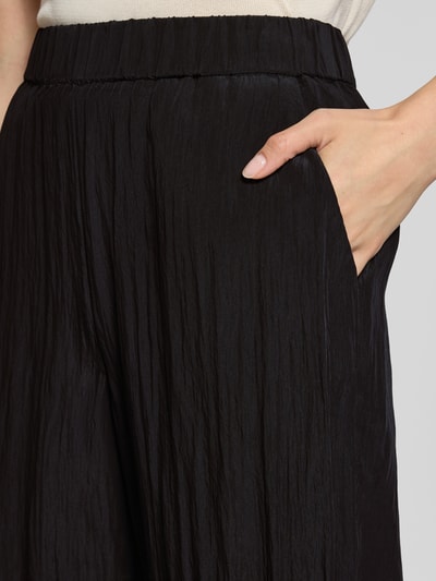 Frauenmodel trägt Stoffhose aus Viskose-Mix Modell 'Cevil' von someday, schwarze Farbe, lockere Passform, Nahaufnahme Oberkörper.