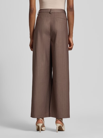 Frauenmodel trägt Wide Fit Hose mit Viskose-Anteil Modell 'Fee' von GUIDO MARIA KRETSCHMER WOMAN in Braun mit Bundfalten, Gesäßtasche, elastischem Material-Mix, Produktdetails aus Kontext, Ganzkörperansicht Rückansicht.