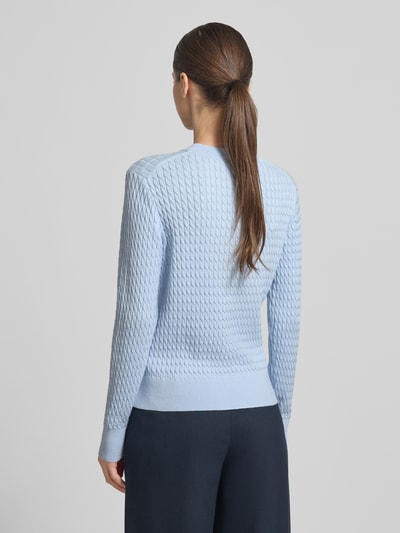 Modelka nosi Slim Fit Pullover aus reiner Baumwolle von Tommy Hilfiger, efekt: jednolity kolor, ścieg warkoczowy, imitacja dzianiny, długi rękaw, detal z logo, okrągły dekolt, wykończenie prążkowane, sweter z bawełny, widok całej sylwetki z tyłu.