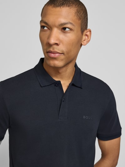 Męski model nosi koszulkę polo Regular Fit Poloshirt aus reiner Baumwolle Modell 'PIO 1' von BOSS Green, efekt: jednolity kolor, kołnierzyk polo, dekolt w serek, listwa guzikowa, krótki rękaw, zakończenie rękawów prążkowane, wykończenie materiału: bawełna, przód ujęcia, górna część ciała.