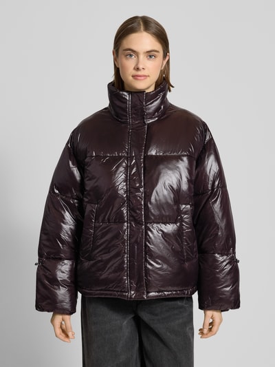 Kobiece modelka nosi Steppjacke mit Stehkragen Modell 'ALLIE' od Noisy May, ciemnofioletowy, błyszczący materiał, widok całej sylwetki z przodu. Relaxed Fit, ukryty zamek, kieszenie boczne, długość tyłu 66 cm, szerokość ramion 56 cm, szerokość klatki piersiowej 66 cm, długość rękawa 56 cm.