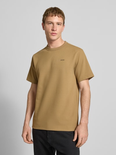 Męski model nosi Regular Fit T-Shirt mit Strukturmuster von G-Star Raw w kolorze beżowym, okrągły dekolt, logo na piersi, długość pleców w rozmiarze M: 71 cm, Ganzkörperansicht von vorne.