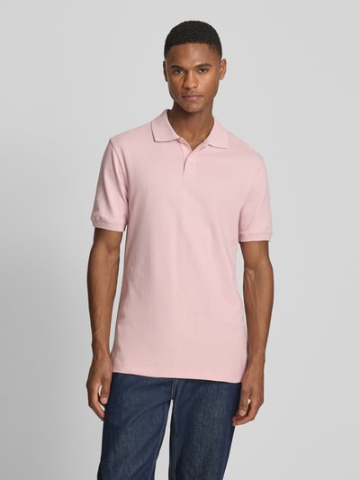 Männermodel trägt Slim Fit Poloshirt mit Label-Stitching von GAP aus Baumwoll-Elasthan-Mix in Rosa, Knopfleiste, Ganzkörperansicht von vorne. Rückenlänge bei Größe M: 70 cm.