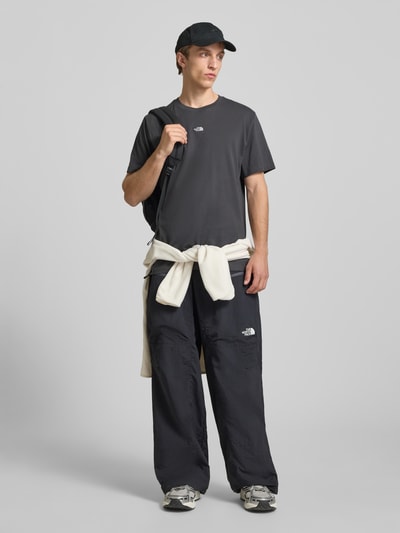 Männermodel trägt T-Shirt mit Logo-Stitching von The North Face in Schwarz, reine Baumwolle, gerader Schnitt, Ganzkörperansicht von vorne.