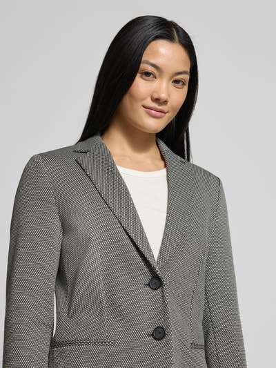 Vrouwenmodel draagt Regular Fit Blazer uit viscosemix Model 'JONALAHRA' van BOSS, all-over motief, reverskraag, machinewasbaar, 2-knoopsluiting, lange mouw, 4-weg stretch. Nahaufnahme Oberkörper.