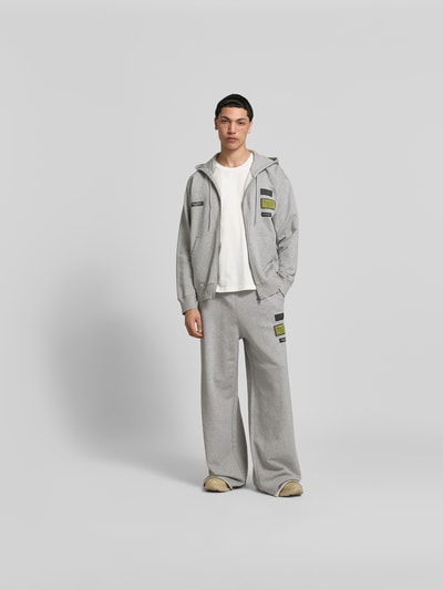 Männermodel trägt Regular Fit Sweatjacke mit Logo-Patch von MM6 Maison Margiela aus reiner Baumwolle, Vorderansicht Ganzkörperansicht.