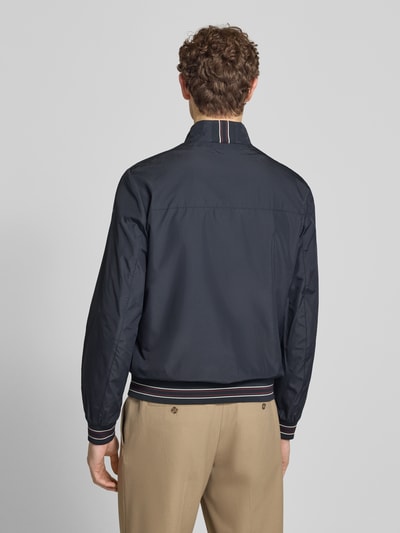 Męski model nosi Blouson mit Stehkragen und Reißverschluss od Geox, granatowy, krój regular fit, długość tyłu 68 cm, szerokość ramion 46 cm, szerokość w rozmiarze M 56 cm, długość rękawa 68 cm, całkowity widok z tyłu.