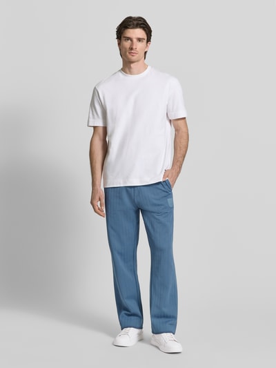 Männermodel trägt Regular Fit Sweatpants aus Baumwoll-Mix Modell 'DAVROPANT' von HUGO, Optik: Unifarben, Muster: gestreift, Label Patch, Label-Stitching, Tunnelzug, Bundabschluss: elastisch, seitliche Eingrifftaschen, Materialverarbeitung: Sweat, Beinabschluss mit Seitenschlitz und Reißverschluss, Ganzkörperansicht von vorne.