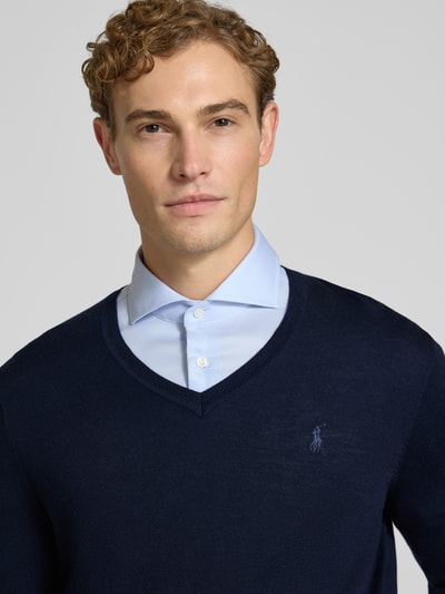 Männermodel trägt Regular Fit Pullover aus reiner Wolle von Polo Ralph Lauren in Dunkelblau, glatte Textur, Nahaufnahme Oberkörper.