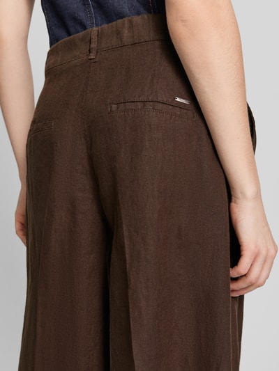 Frauenmodel trägt Loose Fit Leinenhose mit elastischem Bund Modell 'MELLI' von Brax in Braun, reine Leinenstruktur, Detailaufnahme Rückansicht.