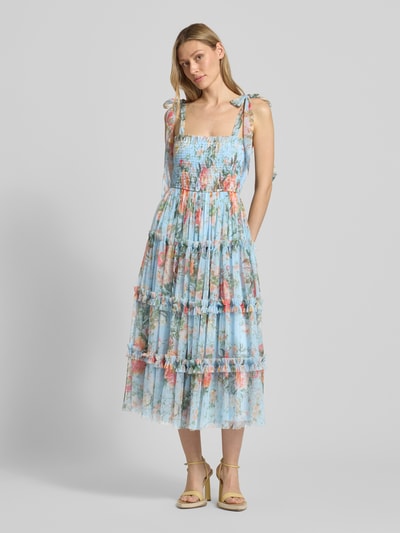 Modelka nosi Knielanges Cocktailkleid mit Smok-Details od LACE & BEADS, siatka, krój A-linii, długość do kolan, stopniowany wygląd, marszczenie, ramiączka z wiązaniem, długość tyłu w rozmiarze S: 100 cm, szerokość w rozmiarze S: 37 cm, pastelowe kolory, kwiatowy wzór, lekka tekstura, widok całej sylwetki z przodu.