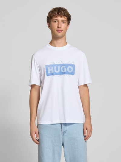 Męski model nosi biały t-shirt Regular Fit T-Shirt aus reiner Baumwolle Modell 'Naxter' von HUGO, gładka faktura, jasnoniebieski nadruk, Męski t-shirt od HUGO Blue, Ganzkörperansicht von vorne.