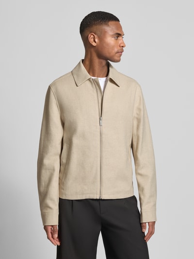 Męski model nosi Regular Fit Jacke mit Viskose-Anteil von JAKE*S STUDIO MEN, beżowa, gładka faktura, materiał elastyczny, krój regular fit, kołnierz wykładany, zamek błyskawiczny, Szerokość w rozmiarze M: 49 cm, szerokość klatki piersiowej w rozmiarze M: 59 cm, długość tyłu w rozmiarze M: 65 cm, długość rękawa w rozmiarze M: 68 cm; całopostaciowe ujęcie z przodu.