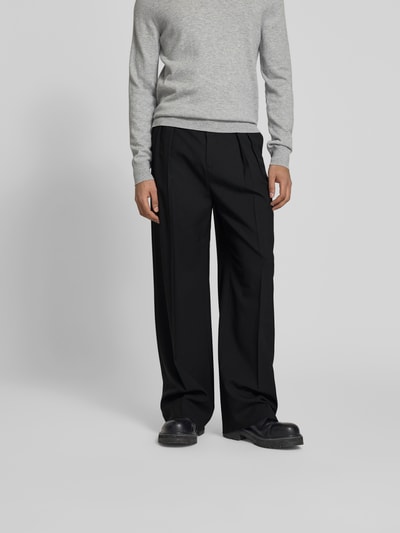 Männermodel trägt Wide Fit Stoffhose aus Woll-Mix von Filippa K, schwarz, Kellerfalten, Gesäßtaschen, Nahaufnahme Unterkörper, Vorderansicht