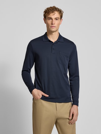 Männermodel trägt Regular Fit Poloshirt aus Baumwoll-Mix von RAGMAN in Dunkelblau, beige Hose, Brusttasche, Nahaufnahme Oberkörper. Herren Poloshirt von RAGMAN, Langarm, elastische Abschlüsse, Rückenlänge bei Größe M 70 cm.