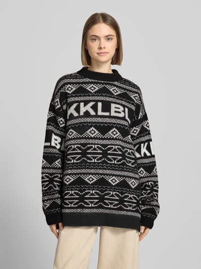 Frauenmodel trägt Jacquard-Strickpullover mit Rundhalsausschnitt von Karo Kauer, schwarz-weißes Muster, Relaxed Fit, Ganzkörperansicht von vorne.