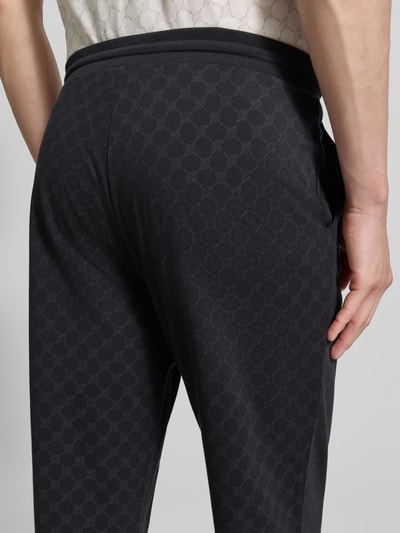 Männermodel trägt Sweatpants mit Logo-Muster und elastischem Bund von JOOP! Collection, reine Baumwolle, Regular Fit, Nahaufnahme Rückansicht.