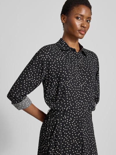 Kobiece model prezentuje Regular Fit Hemdbluse aus reiner Viskose Model 'GILDA' od Soyaconcept, czarne tło z białymi kropkami, krój regular fit, kołnierzyk koszulowy, długi rękaw, listwa guzikowa na całej długości, długość tyłu w rozmiarze S: 57 cm, długość rękawów w rozmiarze S: 57 cm, półzbliżenie od przodu.
