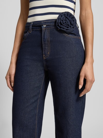Frauenmodel trägt Straight Fit Jeans aus Baumwoll-Mix Modell 'ALLISON' von Vero Moda, Optik: Unifarben, Dark Wash, Gürtel-Applikation mit Rose, 5-Pocket-Design, High-Waist, Denim, Nahaufnahme Oberkörper.