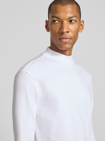 Männermodel trägt Regular Fit Longsleeve aus reiner Baumwolle mit Stehkragen von Christian Berg Men in Weiß, glatte Textur, Nahaufnahme Oberkörper. Rückenlänge bei Größe M: 65 cm, elastische Abschlüsse.