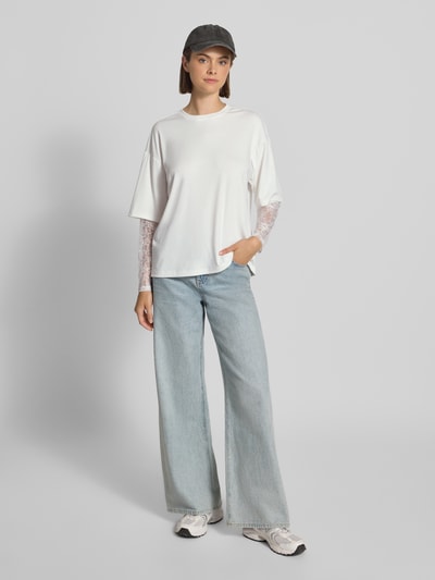 Frauenmodel trägt Regular Fit Langarmshirt mit Viskose-Anteil Modell 'TAHLIA' von ONLY im Damen Langarmshirt Stil, weiß, lockere Form, kombiniert mit heller Jeans, flache Textur, Ganzkörperansicht von vorne.