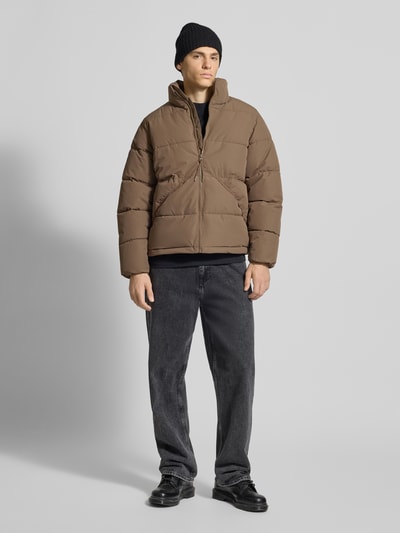 Männermodel trägt Regular Fit Puffer Jacket mit Stehkragen Modell 'PACK' von Only & Sons in Braun, Stepp-Optik, Ganzkörperansicht von vorne.