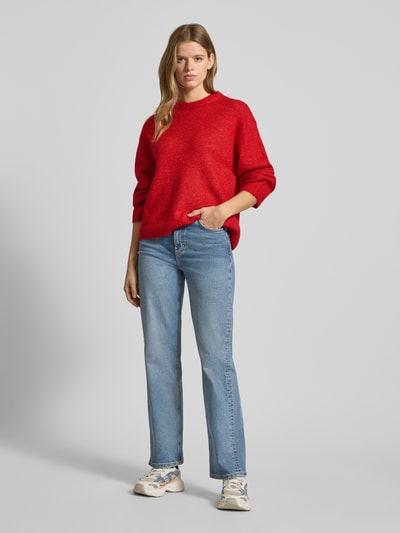 Vrouwenmodel draagt rode Strickpullover met Woll-Anteil van Gina Tricot, los model, geribde boorden, voorkant, full-body shot.