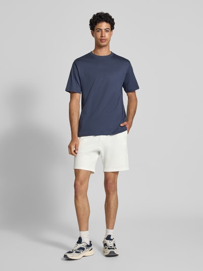 Männermodel trägt Loose Fit Sweatshorts aus Bio-Baumwoll-Mix Modell 'KIAN' von Only & Sons in Weiß, Piqué-Struktur, Ganzkörperansicht von vorne
