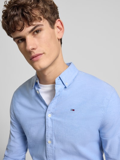 Męski model nosi Slim Fit Freizeithemd aus Oxford marki Tommy Jeans, jasnoniebieski, bawełna z elastanem, widok na górną część ciała z przodu.