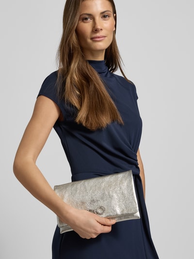 Frauenmodel trägt Clutch aus echtem Leder Modell 'Mimos' von Abro mit Zierschleife und Strasssteinbesatz, silberfarben, Nahaufnahme Oberkörper.
