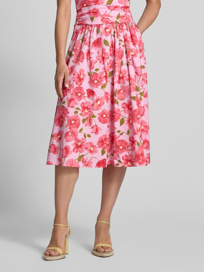 Frauenmodel trägt Midirock im Allover-Look Modell 'CASTLE' von MANGO aus reiner Baumwolle, pink mit roten Blumen, A-Linie, Nahaufnahme Unterkörper.