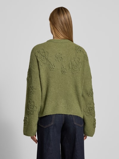 Frauenmodel trägt Strickpullover mit Stitchings Modell 'Miabelle Hope' von MSCH Copenhagen in Olivgrün, Material-Mix mit Alpaka-Anteil, Ganzkörperansicht Rückansicht.