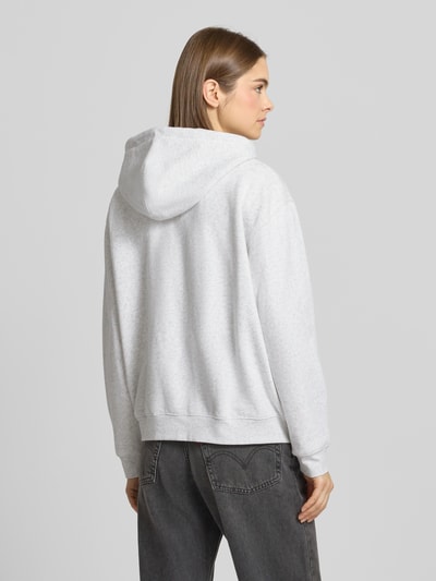 Vrouwenmodel draagt Sweatjacke mit Kapuze van Levi's®, lichtgrijs, katoenmix, losse pasvorm, geribbelde boorden, rugaanzicht.