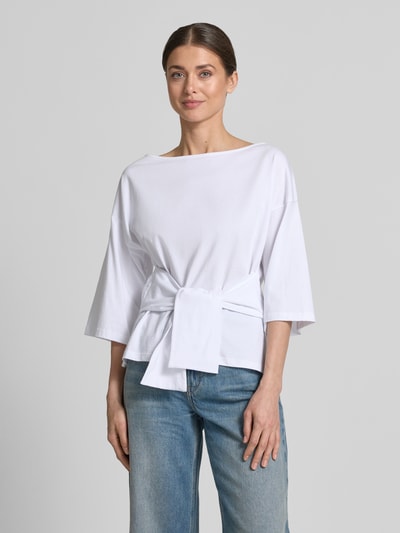 Frauenmodel trägt Shirt mit U-Boot-Ausschnitt Modell 'Dajana' von GUIDO MARIA KRETSCHMER WOMAN aus reiner Baumwolle, taillierter Schnitt, weiße Farbe, glatte Textur, 3/4-Arm, Raffung, Rückenlänge bei Größe 36: 56 cm, Nahaufnahme Oberkörper.