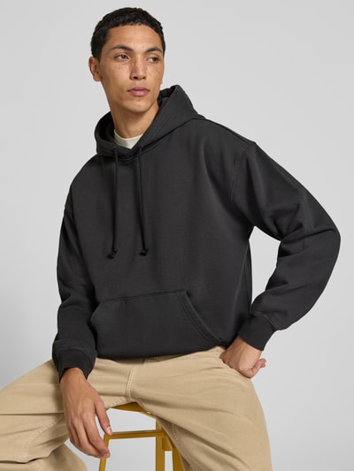 Männermodel trägt Relaxed Fit Hoodie aus Baumwoll-Mix Modell 'JET BL' von Levi's®, schwarz, beige Hose, Ganzkörperansicht von vorne.